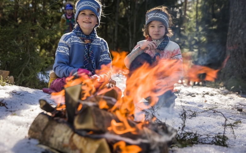 To små speidere sitter foran bålet