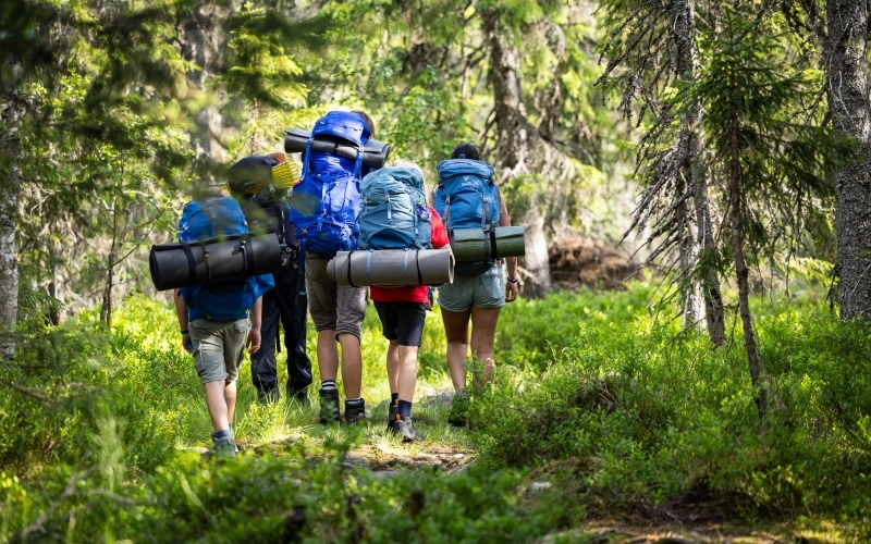 Speidere med sekk på tur i skogen